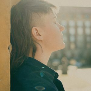Maria Milvus leaning on a wall, eyes closed